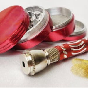 May include: A red metal grinder with a silver metal screen and a silver metal pipe with a red and white design. The pipe has a small metal screen on the end.