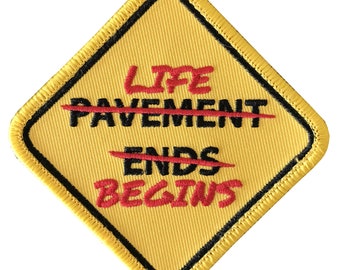 Broderad lapp med texten Pavement Ends / Life Begins