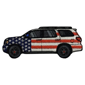 May include: A black SUV with a red, white, and blue American flag design. The car is a side view and the flag is on the side of the car.