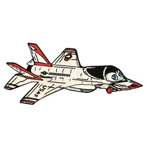 Może przedstawiać: Biało-czerwony, kreskówkowy samolot myśliwski z czarnymi akcentami i niebieskimi oczami. Samolot ma napis "USAF" na boku.