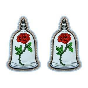 May include: Two decorative pins featuring a red rose inside a glass bell jar. The rose has green leaves and a stem. The jar is outlined in silver and has a light blue border.