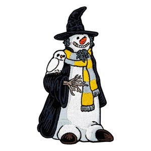 May include: An embroidered patch featuring a white snowman wearing a black pointed hat, a black robe, and a yellow and gray striped scarf. The snowman has an orange carrot nose, a twig arm, and a small white owl perched on its shoulder.