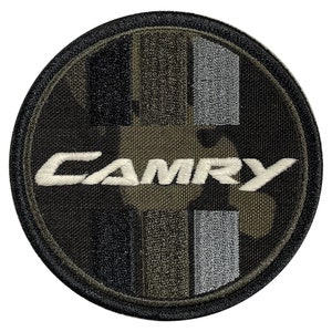 May include: A round, black and green camouflage fabric patch with a white embroidered "CAMRY" logo.