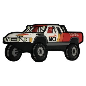 Puede incluir: Un camión de juguete blanco y rojo con ruedas negras y las palabras "MCI" y "TOYOTA" en el lateral.