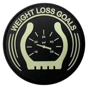 May include: Black and white weight loss goal patch with a gauge design. The gauge reads "psi" and has numbers from 10 to 50. The text around the gauge reads "Weight Loss Goals".