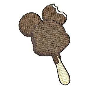 May include: An embroidered patch shaped like a chocolate-covered ice cream bar on a stick. The brown ice cream has a rounded top with a bite taken out of the upper right side, revealing a white interior. The stick is light cream colored.