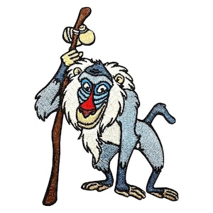 Puede incluir: Parche bordado con un babuino de dibujos animados en tonos azules, blancos y marrones. El babuino sostiene un bastón de madera con un orbe beige en la parte superior. El babuino tiene una nariz roja y una expresión sonriente.