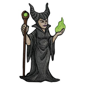 Könnte beinhalten: Gestickter Aufnäher mit einer stilisierten Darstellung einer Figur mit schwarzen Hörnern, einem schwarzen Gewand und einem Stab mit einer grünen Kugel. Die Figur hält eine grüne Flamme. Der Aufnäher befindet sich auf weißem Hintergrund.