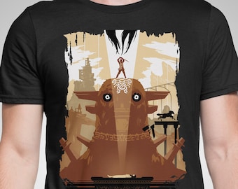 May include: A black t-shirt with a graphic print of a large, brown, creature with a human figure standing on its head. The creature has large, white eyes and a textured surface. The graphic is set against a background of a cityscape with a sunset.