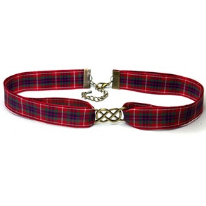 May include: Red and green tartan ribbon choker necklace with a gold infinity symbol charm.