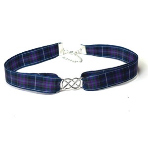May include: A tartan choker necklace with a silver-tone infinity knot. The navy blue, purple, and white plaid pattern is visible on the ribbon. The necklace has a silver chain for adjustment.