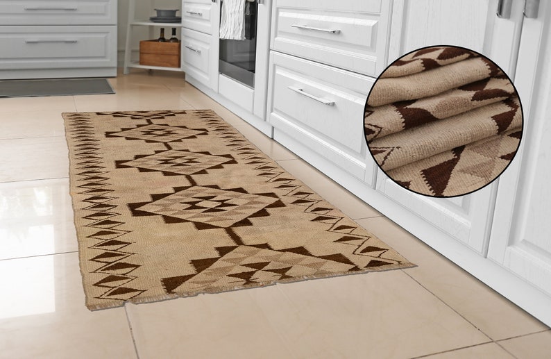 May include: A beige and brown geometric patterned runner rug with a fringed edge. The rug is folded in a circle in the upper right corner of the image.