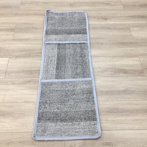 Peut inclure: Un tapis gris et blanc à rayures avec trois compartiments rectangulaires. Le tapis a une bordure bleu clair.