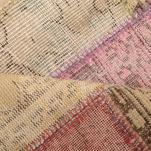 Puede incluir: Primer plano de una alfombra tejida multicolor con un diseño de patchwork. La alfombra presenta tonos de rosa, marrón, beige y blanco.