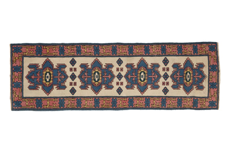 K&ouml;nnte beinhalten: Ein langer, schmaler Teppich mit traditionellem persischem Design. Der Teppich hat einen cremefarbenen Hintergrund mit einem blauen, roten und gelben Muster. Der Teppich ist perfekt, um jedem Raum einen Hauch von traditionellem Stil zu verleihen.