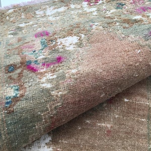 May include: A vintage rug with a faded floral pattern in shades of pink, blue, and green. The rug has a worn and distressed look, giving it a rustic charm.