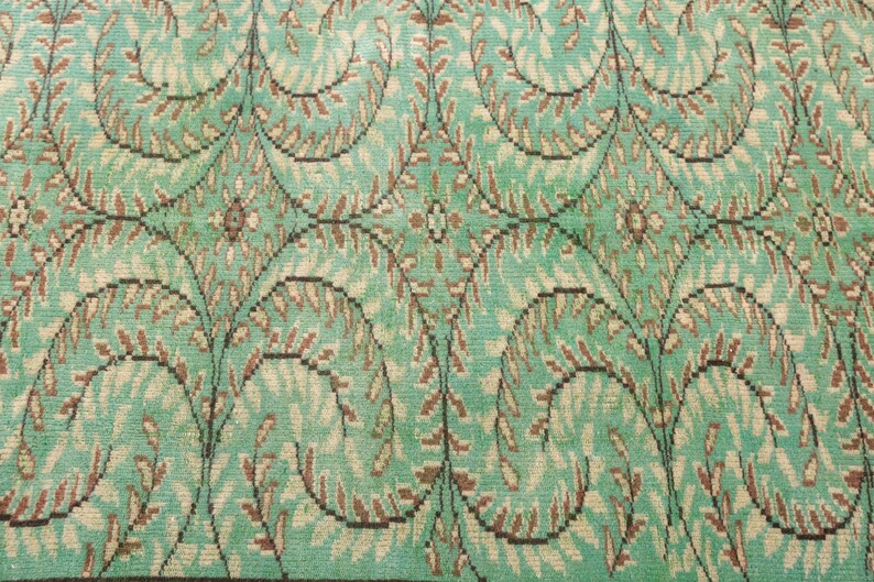 May include: A vintage rug with a repeating pattern of brown and green leaves on a light blue background.