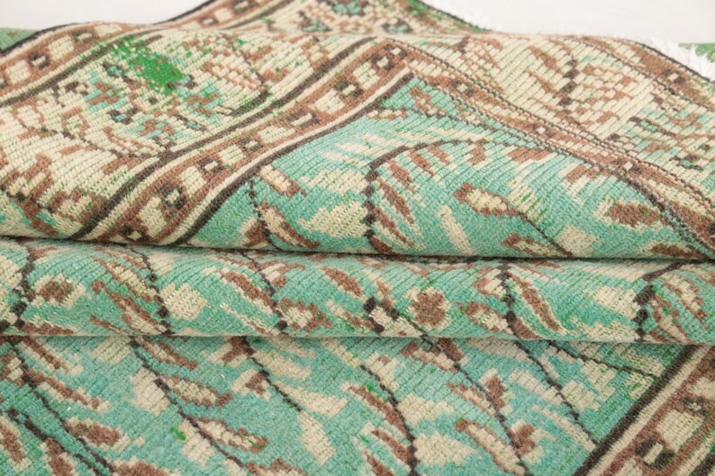 May include: A close-up of a folded turquoise and brown patterned rug with a geometric design.