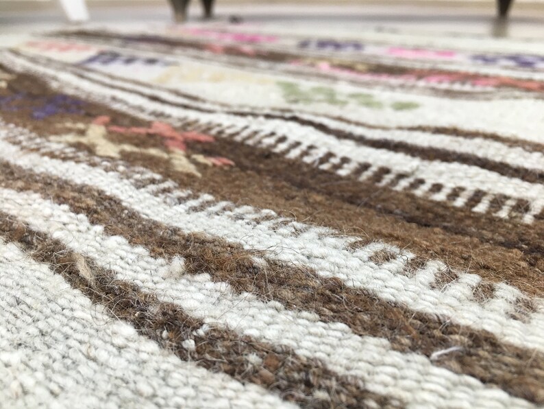 May include: Close-up of a woven rug with brown and white stripes. The rug has a textured surface and a subtle pattern.