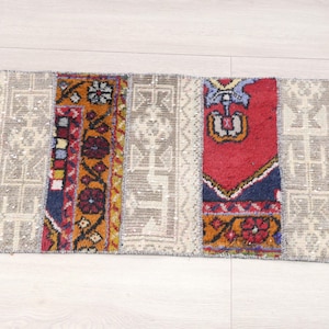 Puede incluir: Una alfombra rectangular de patchwork con fondo blanco y patrones geométricos coloridos en rojo, azul, amarillo y naranja.