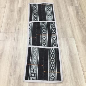 Peut inclure: Textile rectangulaire noir et blanc à motifs géométriques et bordure gris clair. Le motif présente des rayures verticales avec des motifs répétitifs. Il pourrait s'agir d'un tapis ou d'une tenture murale décorative.