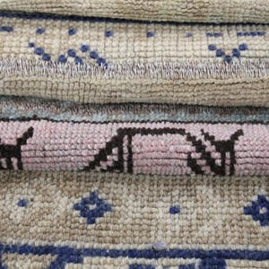 Peut inclure: Gros plan sur plusieurs tapis enroulés avec des motifs complexes. Les tapis présentent une variété de couleurs, notamment beige, bleu et rose. Les motifs comprennent des formes géométriques et des motifs floraux.