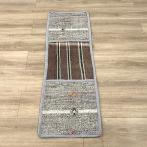 Puede incluir: Una alfombra de corredor gris y blanca a rayas con una sección a rayas marrón y blanca en el medio. La alfombra tiene un borde gris y está hecha de tejido tejido.