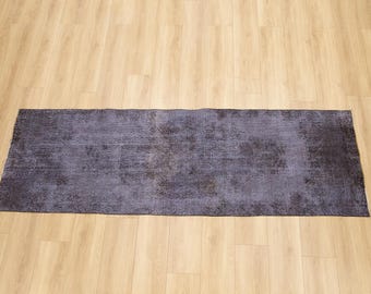 May include: A rectangular area rug featuring a deep purple and charcoal gray color palette. The rug displays a faded, distressed pattern with intricate, worn-out floral and geometric motifs distributed across the entire surface of the textile.