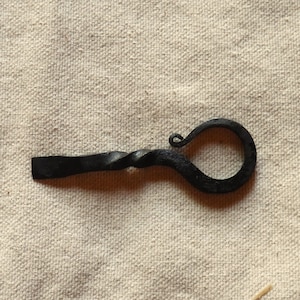 May include: A black metal bottle opener with a twisted handle and a loop at the end.