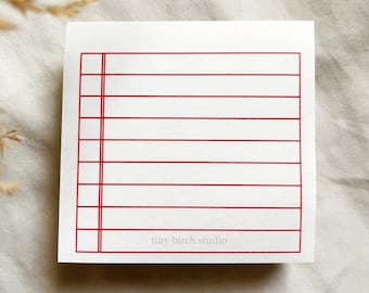 Op de afbeelding: Een wit notitieboekje met rode lijnen en de tekst "tiny birch studio" onderaan.