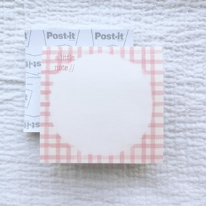 May include: A pink and white gingham notepad with a circle in the center and the text "a little note //" at the top.
