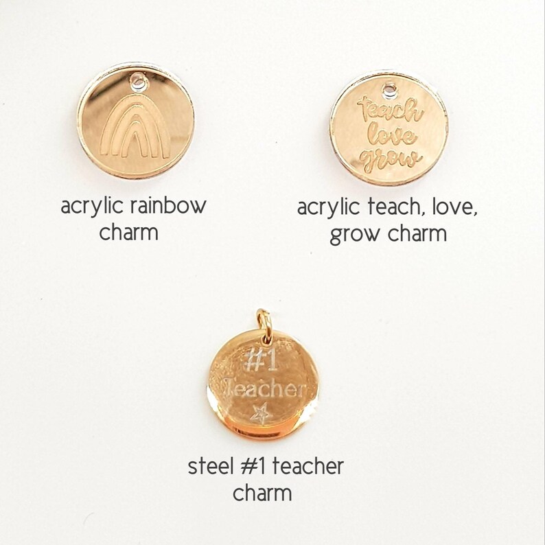 May include: Three gold charms for a necklace or bracelet. The first charm is a rainbow, the second charm says "teach love grow", and the third charm says "#1 teacher" with a star.