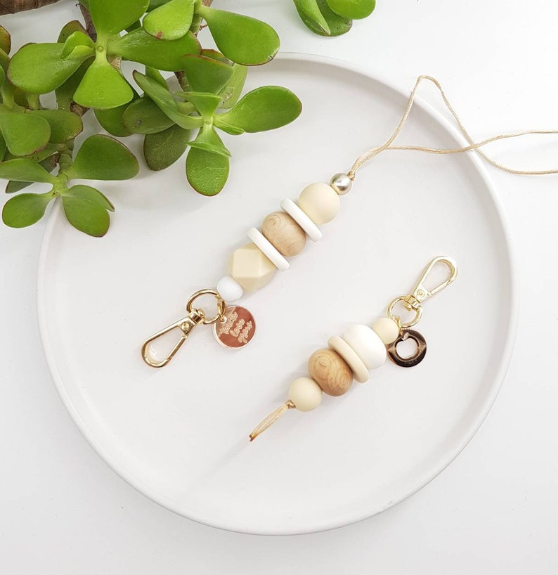 May include: Two wooden bead keychains with gold accents. One keychain has a small gold charm with the text "Love You" on it. The other keychain has a small gold circle charm.