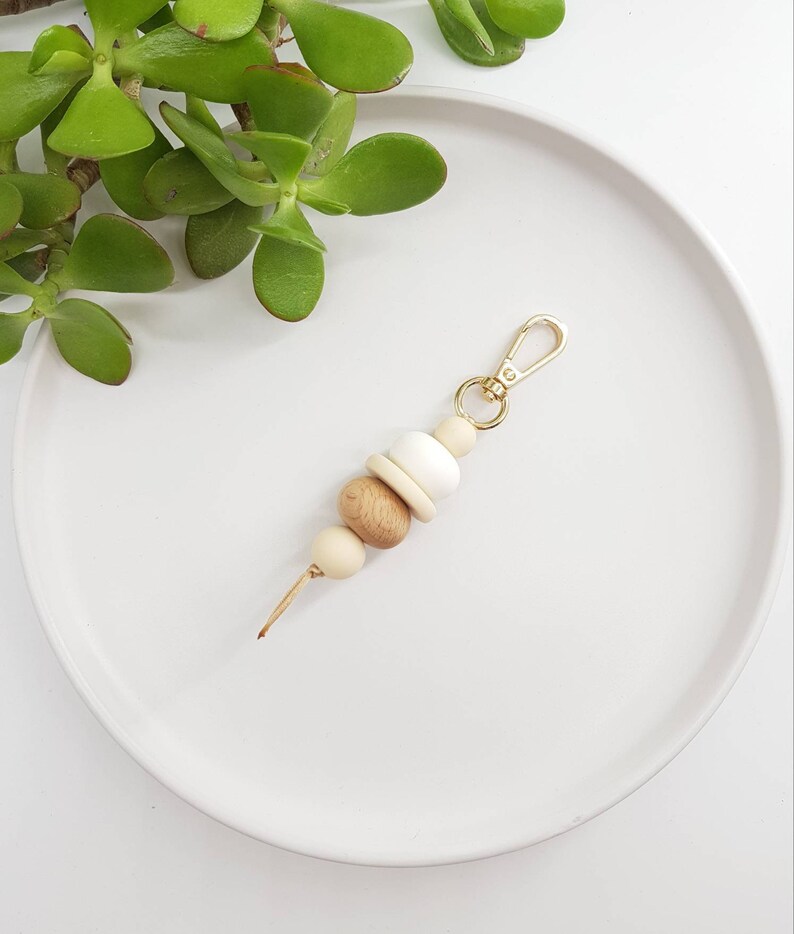May include: A wooden bead keychain with a gold metal clasp. The beads are in shades of brown and white.