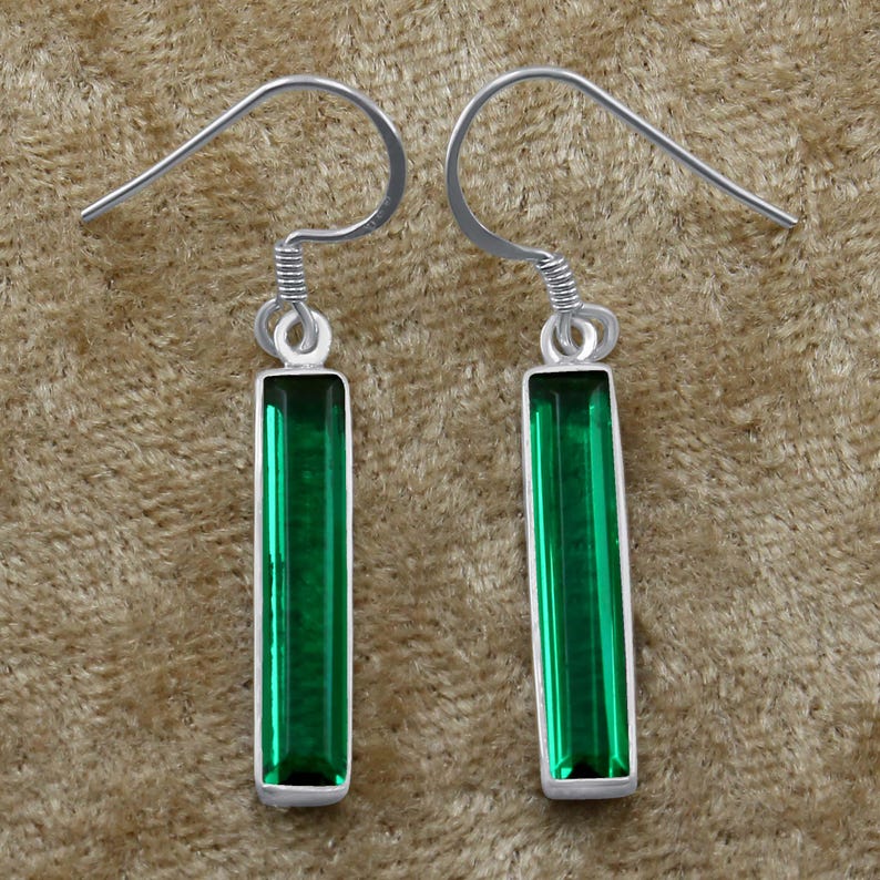 May include: A pair of silver dangle earrings with green rectangular gemstones.
