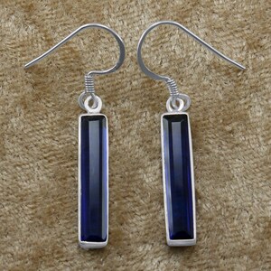 May include: A pair of silver dangle earrings with dark blue rectangular gemstones.