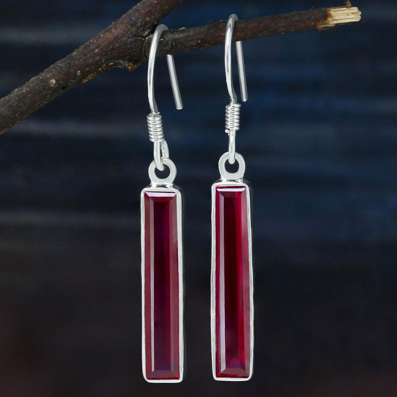 May include: A pair of silver dangle earrings with long, rectangular red gemstone drops.