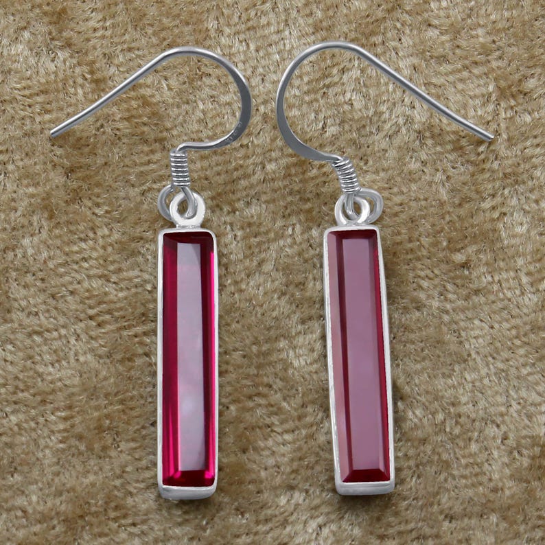 May include: A pair of silver dangle earrings with rectangular red gemstone drops.