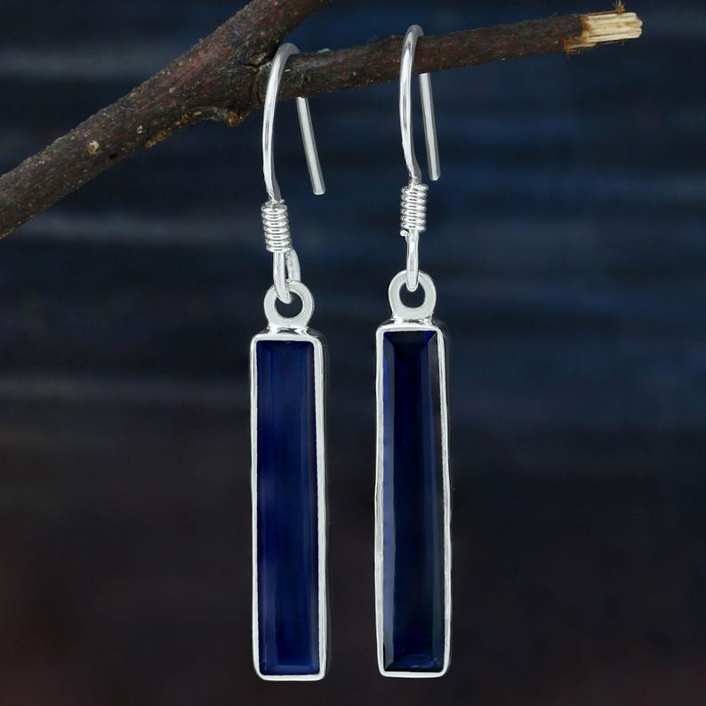 May include: A pair of silver dangle earrings with dark blue rectangular gemstones.