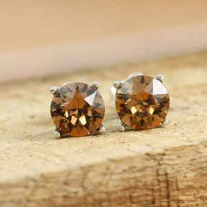 May include: A pair of silver stud earrings with round, brown, faceted gemstones.