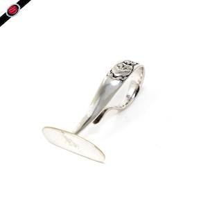 Peut inclure: Une bague en argent avec un motif décoratif sur la bande. La bague est en forme de doigt avec une base plate.