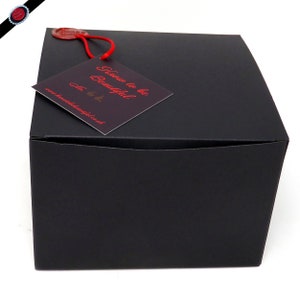 May include: A black, square gift box with a red tag attached. The tag reads "Know to be Beautiful" in red script, with a website address below. A red wax seal is also attached to the box.