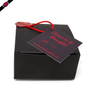 May include: A black box with a red wax seal and a red string tied around it. The box has a tag attached to it that says "Know to be Beautiful" and "No. 73" with the website address "www.knowtobebeautiful.co.uk".