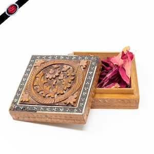 May include: A wooden box with intricate carvings and inlaid details. The box is open and filled with dried rose petals.