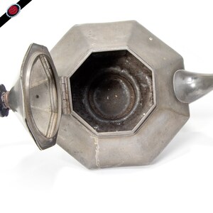 May include: A silver octagonal teapot with a hinged lid. The teapot is open and the inside is visible.