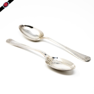 May include: Two silver spoons with ornate designs. The spoons have a rounded bowl and a long, slender handle.