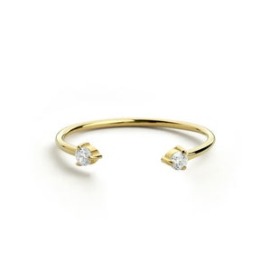 May include: A gold ring with two small diamonds set into the band. The ring is open on one side, making it adjustable.