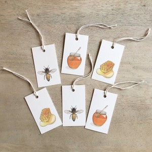 May include: Six white gift tags with string attached. Each tag has a different image of a honeybee, honeycomb, or honey jar. The images are hand-drawn in watercolor and feature warm yellow, orange, and brown colors.