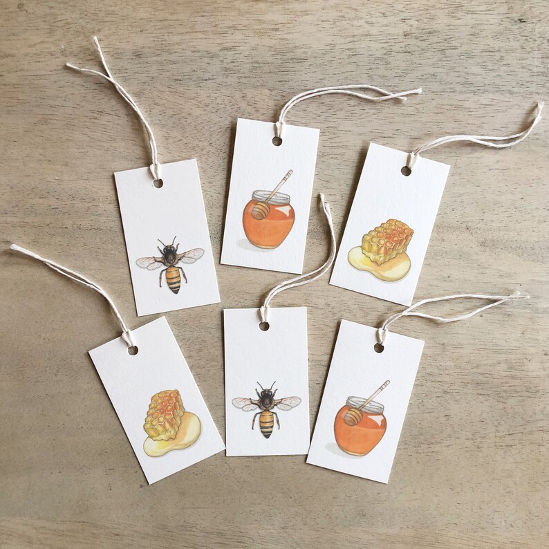 May include: Six white gift tags with string attached. Each tag has a different image of a honeybee, honeycomb, or honey jar. The images are hand-drawn in watercolor and feature warm yellow, orange, and brown colors.