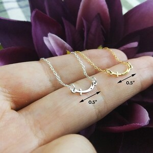 May include: Two delicate silver and gold necklaces with a simple smile design. Each necklace is 0.5 inches long.
